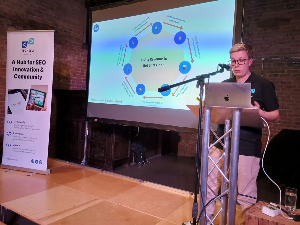 Nikki Halliwell on stage at TechSEO North with the brand banner alongside